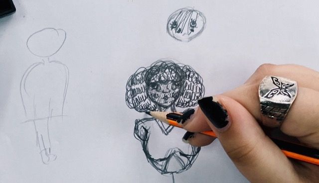 Imagen de una mano con un lápiz, dibujando una figura de una joven con pelo enmarañado.